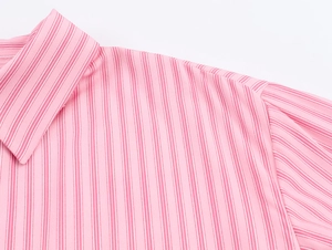 Dettaglio del colletto e della spalla di una camicia a righe rosa e bianche, trama del tessuto