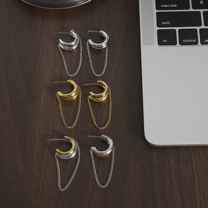 Double C tassel stud earrings in silver, gold, and mixed metal tones on wooden surface