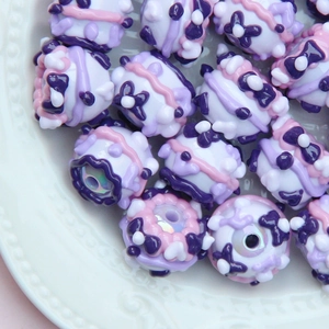 Macro shot of purple hand-painted beads with floral patterns for DIY jewelry making