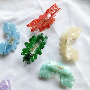 Pinze per capelli ondulate colorate in rosso, blu, verde e bianco su sfondo di tessuto