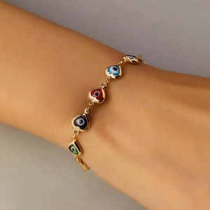 Close-up of gold chain bracelet with colorful enamel heart-shaped evil eye charms