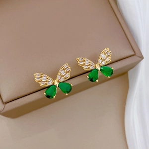 Macro shot of gold butterfly earrings with emerald pear gems and sparkling zircon stones