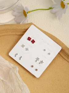 Detail view of a 6-pair silver earring set with heart and clover designs in a cork tray