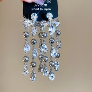 Detailed view of S925 silver fringe earrings with teardrop crystals on a display card