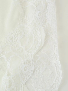 Close-up of intricate white floral lace texture and scalloped edges on the camisole top
