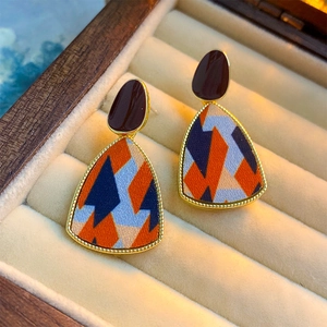Close-up of geometric fabric inlay on triangle earrings inside a velvet jewelry box