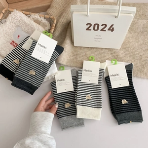 Detailed view of assorted striped cotton socks with cute bear embroidery in a lifestyle setting