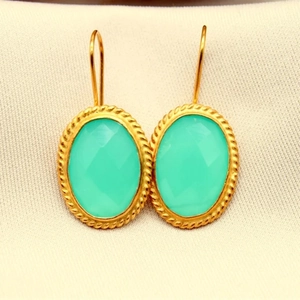 Detailed close-up of oval teal crystal earrings with gold rope border and ear hook design