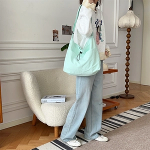 Dettaglio di una grande borsa in tela verde menta con coulisse posta su una sedia