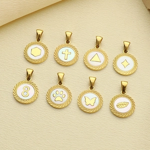 Détail de pendentifs ronds en acier doré avec nacre blanche et divers motifs gravés