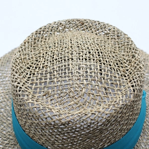 Detailed macro shot of hollow-out straw weave and teal ribbon band on the sun hat
