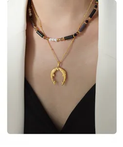 Close-up of double-layered necklace with natural pearls and golden fishtail pendant