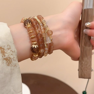 Close-up of elegant beaded layered bracelet with crystal charms and lotus leaf pendants