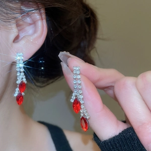 Detail shot of long tassel earrings featuring red teardrop stones and silver rhinestones