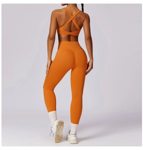 Detail of orange cross-back sports bra and high-waist lifting yoga leggings on model