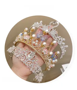 Detailed close-up of golden pearl butterfly crown and silver rhinestone tiara set