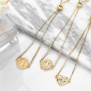 Detailed shot of gold-plated Virgin Mary and heart charms with colorful zircon accents