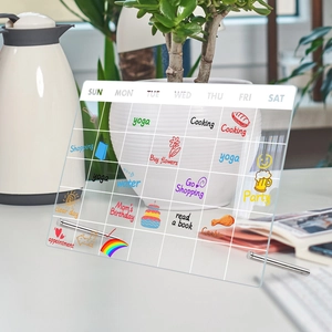 Clear acrylic weekly planner board with metal stand and handwritten schedule notes