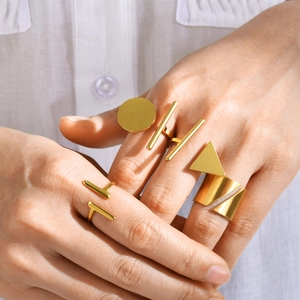 Close-up of minimalist gold geometric rings showing polished finish on a model hand
