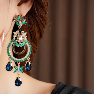 Gros plan de boucles d'oreilles vintage avec cristaux verts et bleus sur un mannequin