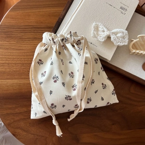 Floral cotton drawstring pouch with red patterns on rustic wooden table background