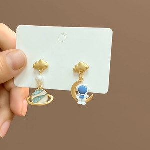Asymmetric gold earrings featuring a cute astronaut, blue planet, and moon with pearls
