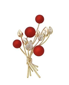 Close-up of sparkling berry brooch with red beads and rhinestone leaves on gold stem