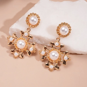 Macro detail of retro pearl cross earring on marble stone base with golden alloy frame