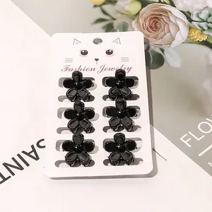 Set of six mini black flower hair claw clips for girls on a decorative display card