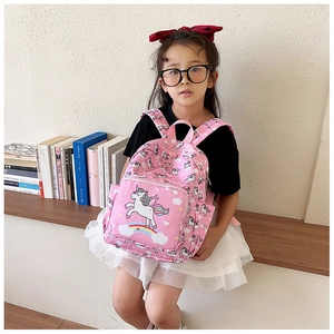 Pink toddler backpack with cartoon unicorn print worn by a little girl in a cozy room