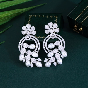 Close-up of silver flower pearl earrings with sparkling zircon on a dark green box