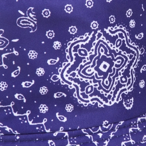 Detailed close-up of dark purple paisley patterned cotton fabric with reinforced double stitching