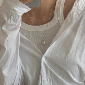 Close-up of elegant round pearl pendant necklace on a silver chain worn by a model