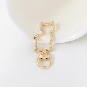Close-up of golden cat-shaped metal clasp with a swivel ring on a white ceramic plate
