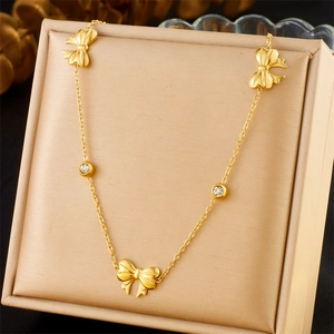 Golden bow necklace with sparkling zircon stones displayed on a premium beige jewelry box