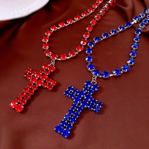 Detail of cross pendants with red and blue crystals on dark satin background