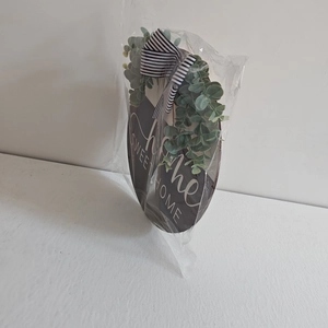Detail of wooden home door wreath with eucalyptus leaves and striped bow in clear packaging