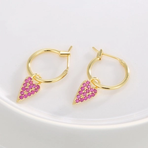 Elegant gold heart earrings with pink zircon stones on a white ceramic tray display