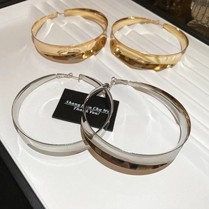 Flat lay of oversized polished hoop earrings in gold and silver finish on display
