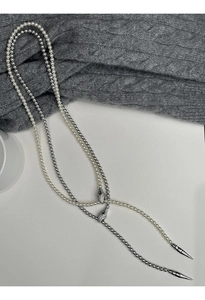 Macro detail of pearl and silver bead snake necklaces with green stone eyes and metal accents