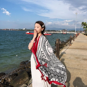 Detailed view of red and black ethnic scarf with fringe on a model at the seaside