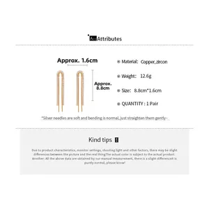 Detailed view of U-shaped gold tassel earrings with size dimensions and copper material info