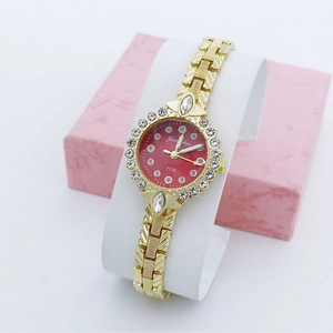 Détail d'une montre à quartz à cadran rouge avec lunette sertie et bracelet doré ciselé