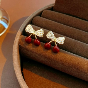 Vue macro de boucles d'oreilles cerise à nœud plaquées or avec zircons sur velours