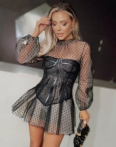 Detail of black mesh lace dress featuring polka dots and sheer puff sleeves with waist belt