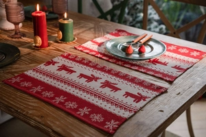 Close-up of red and beige Christmas placemats with jacquard reindeer and snowflake patterns