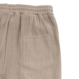 Detail of men's ribbed knit trousers showing elastic waistband and back patch pocket