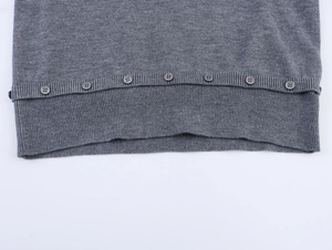 Détail de pull en maille grise avec ourlet côtelé et boutons ronds décoratifs