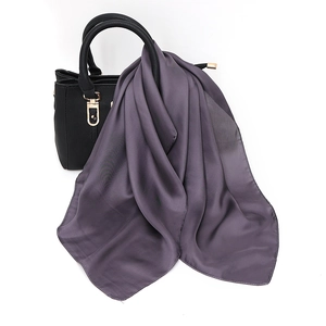 Detailed view of dark purple satin scarf draped on a handbag showing silky texture