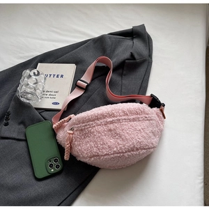 Detailed view of pink plush crossbody chest bag with adjustable strap on a grey blazer